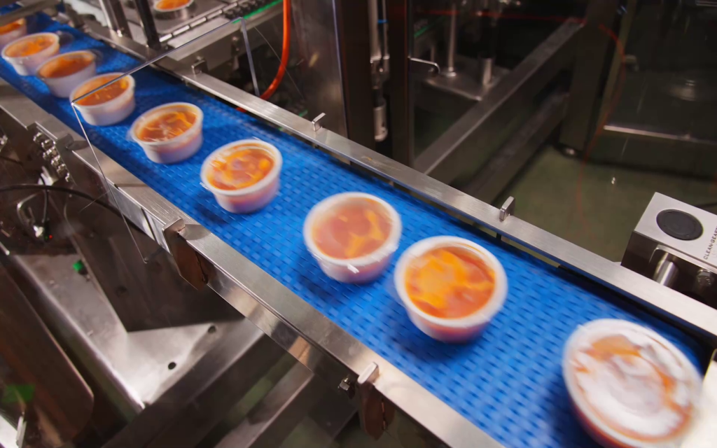 Filled and sealed food containers moving quickly on an assembly line