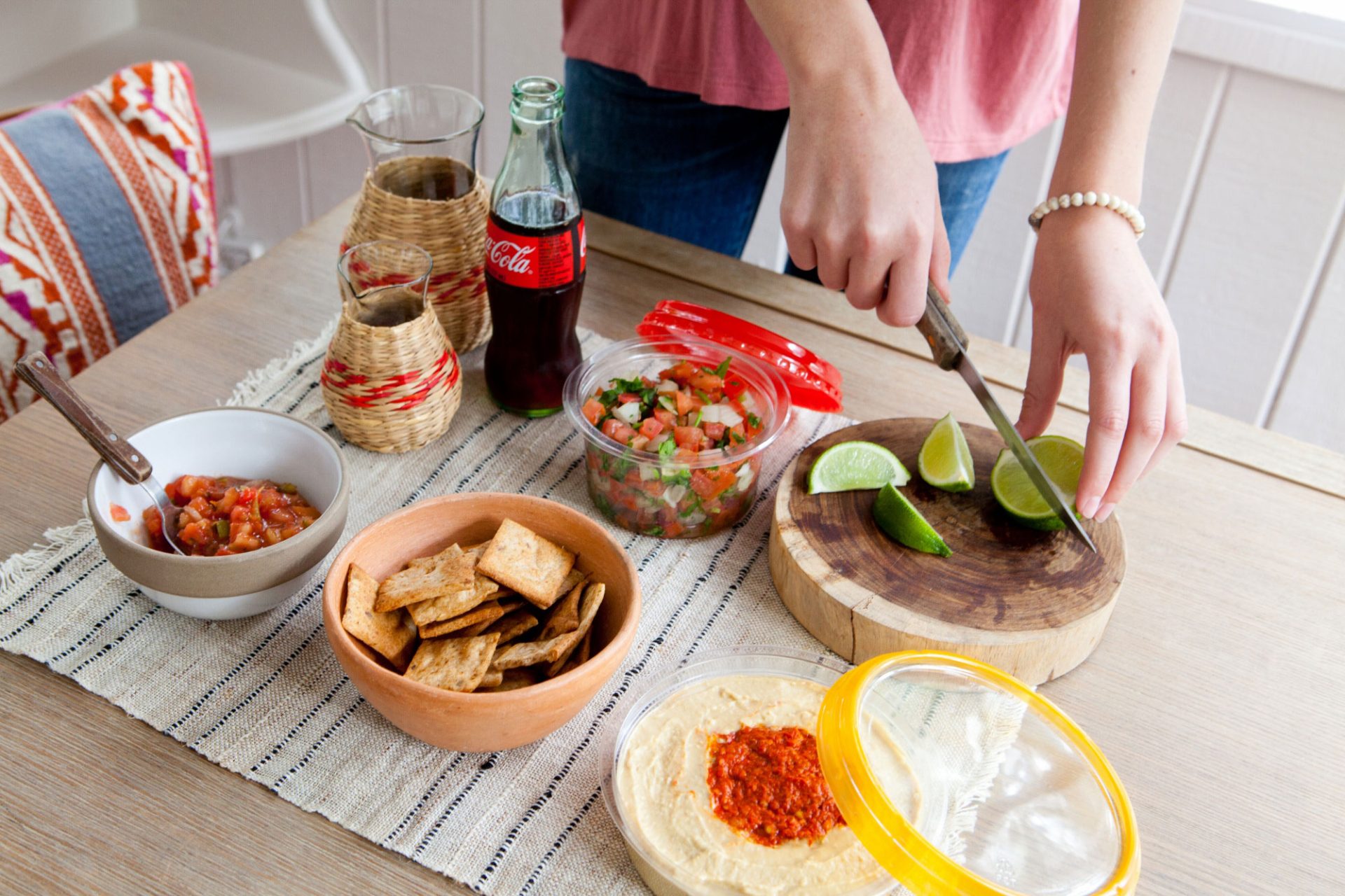A woman cutting limes on a table with several other prepared snacks