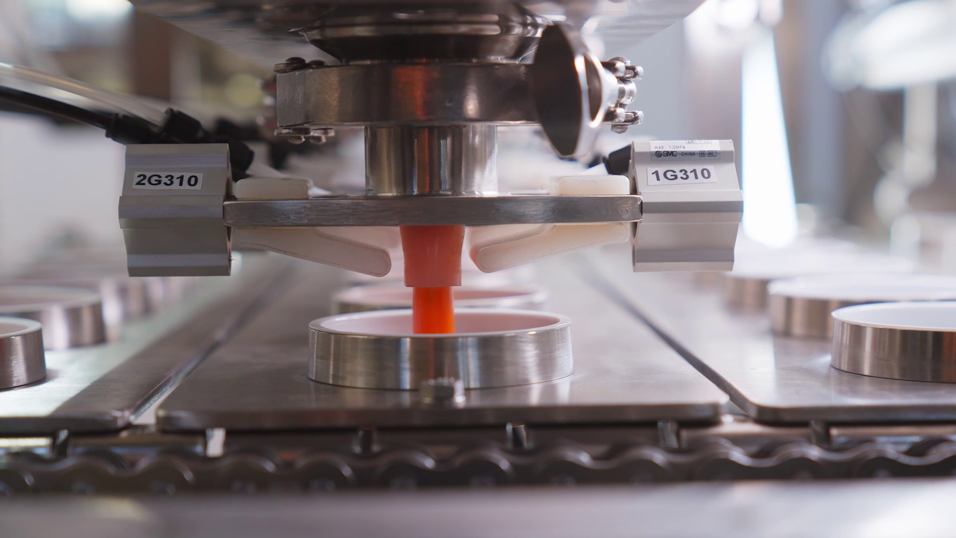 A machine pouring liquid into a container as a step in the assembly line