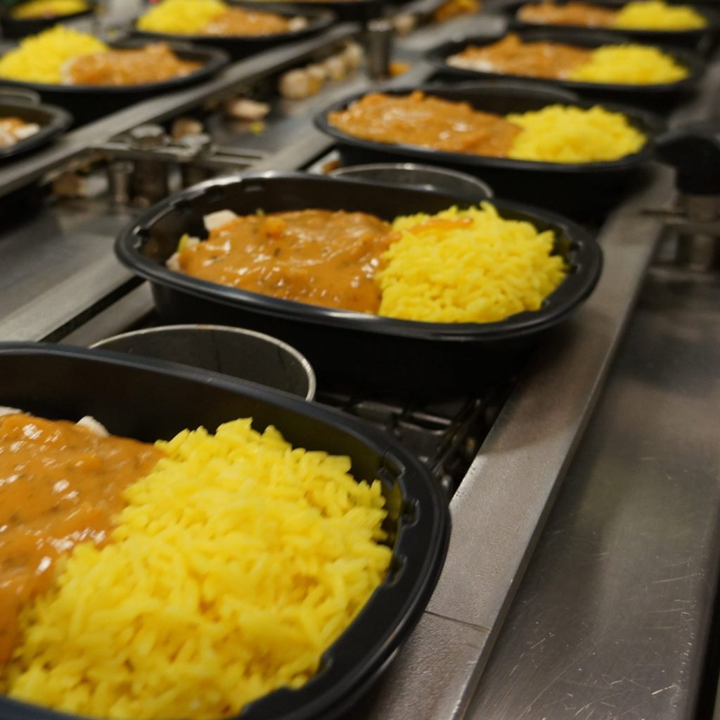 Several ready meals being packed on an assembly line
